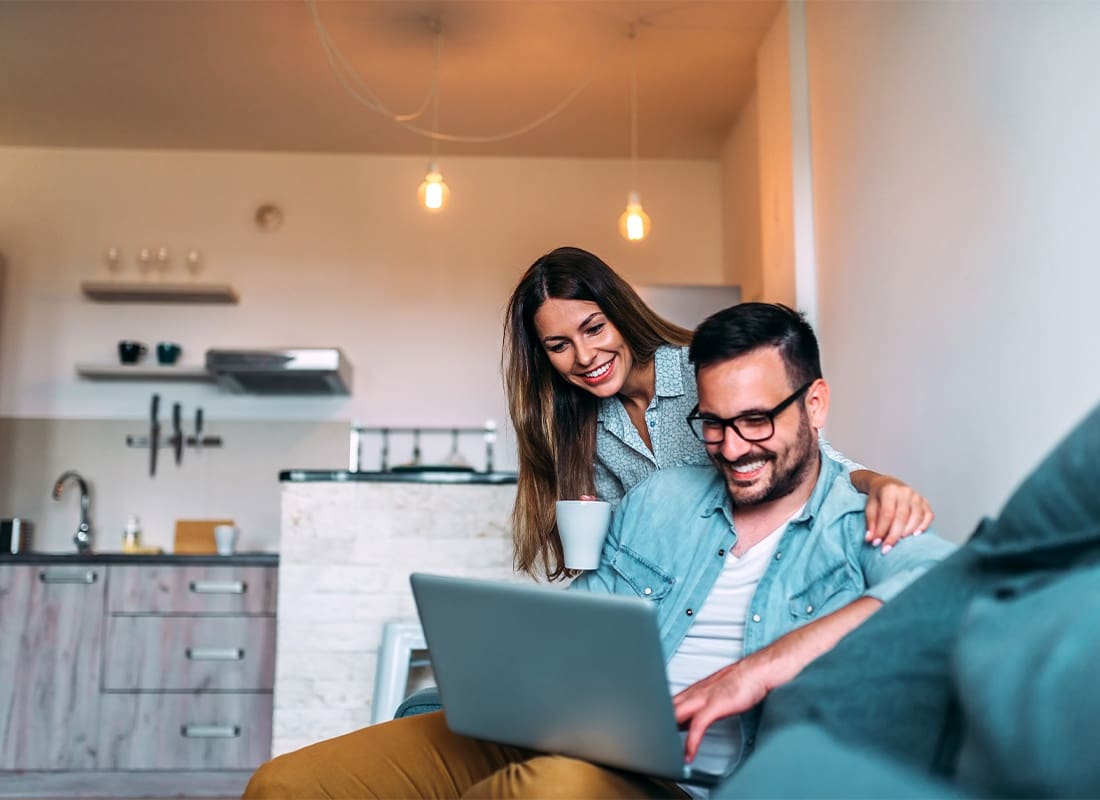 We Are Independent - Young Couple Using a Laptop While Sitting on the Sofa at Home